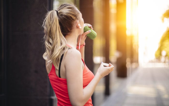 Young woman drinking green juice before exercising