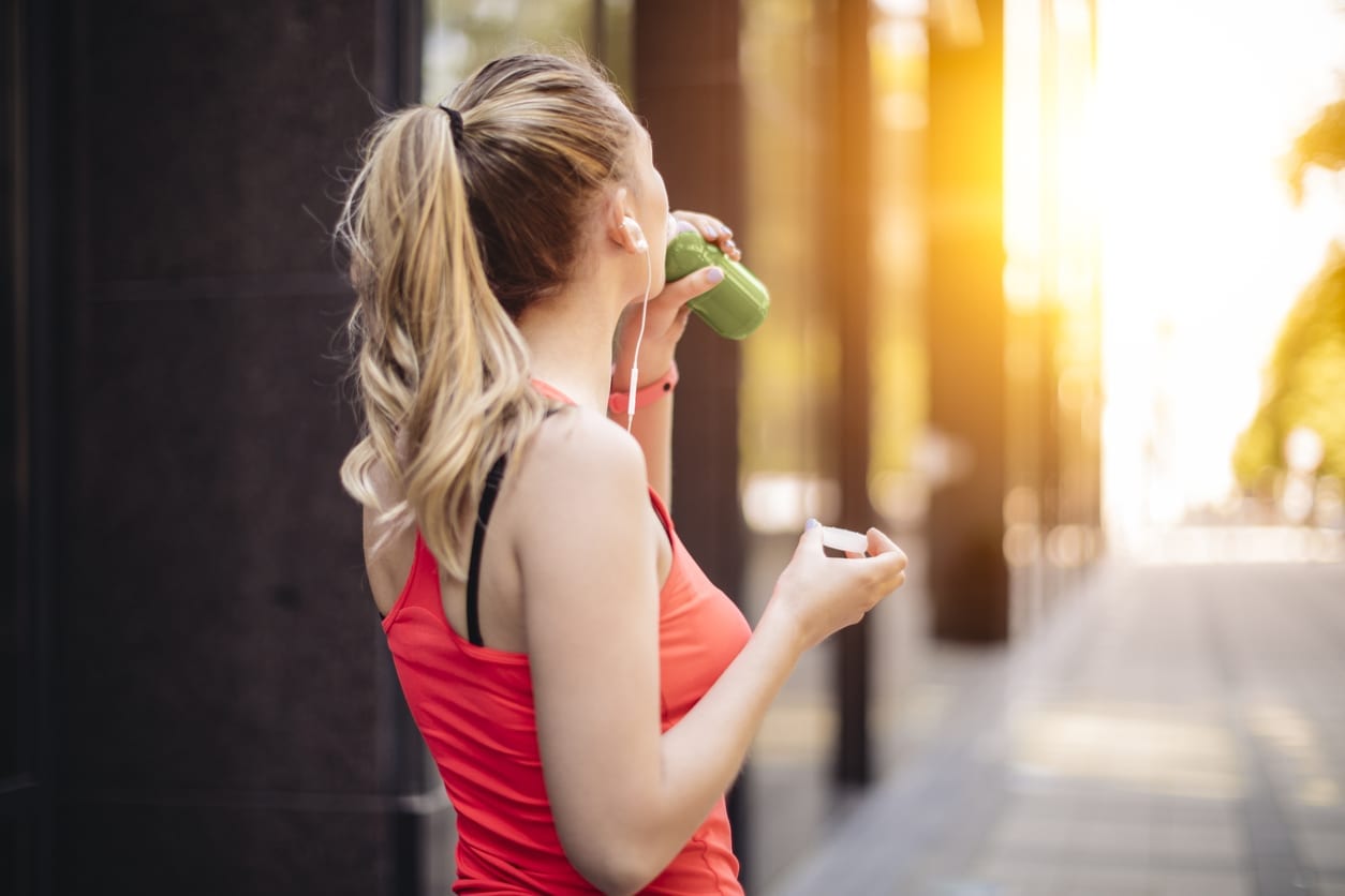 Young woman drinking green juice before exercising